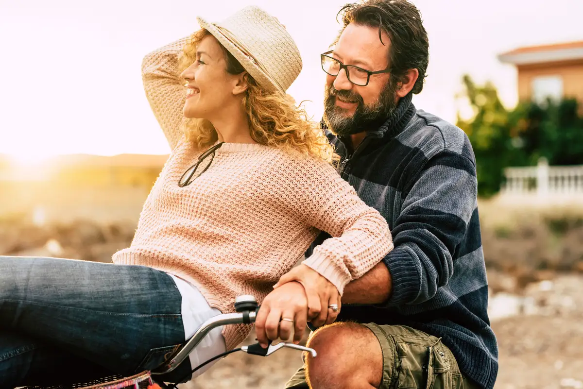 Pareja de 50 años compartiendo una bicicleta, disfrutando de su jubilación temprana gracias a los ahorros logrados con el movimiento FIRE.